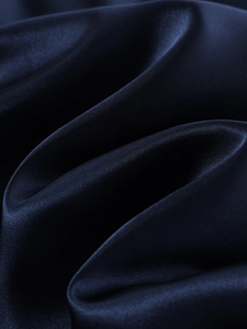 Close-up of dark blue satin fabric texture with silky sheen and elegant folds