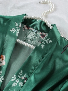 Dettaglio della vestaglia in raso di seta con fiori rosa e motivi a foglie bianche