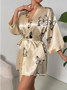 Close-up of champagne silk satin robe featuring elegant black and yellow butterfly patterns