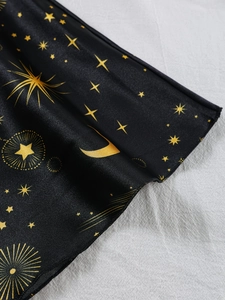 Détail du tissu en satin noir avec imprimés dorés de lune et d'étoiles et texture lisse