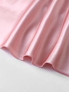 Détail de pyjama en satin rose montrant l'ourlet ondulé et les coutures de précision