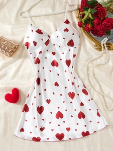 Dettaglio di camicia da notte in seta bianca con cuori rossi e accessori di perle