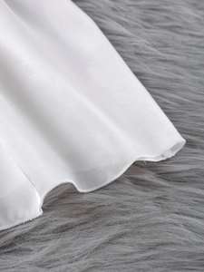 Nahaufnahme von weißem Satin-Schlafanzugstoff mit hochwertiger Wellensaum-Verarbeitung