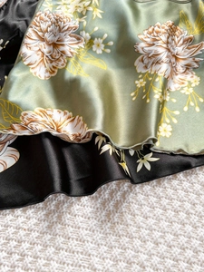 Détail du tissu satiné floral avec ourlet à volants et texture soyeuse brillante