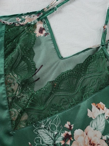 Dettaglio del top in raso verde scuro a fiori con rifiniture in pizzo raffinato sullo scollo a V