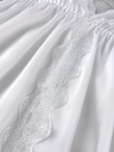 Nahaufnahme des weißen Satin-Schlafanzugs mit feiner Spitze auf weichem Plüsch-Hintergrund