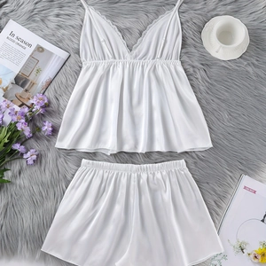 Weißes Satin-Pyjama-Set mit Spitzenbesatz-Top und Shorts auf weichem Teppich
