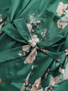 Close-up of dark green faux silk robe featuring floral and butterfly art prints