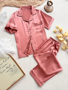 Detail of pink satin pajama set featuring black contrast piping and classic button-down design