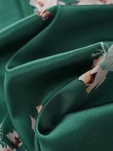 Detailed view of dark green faux silk fabric with elegant floral print and satin luster