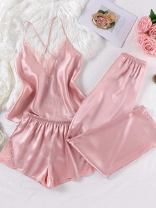 Detailed flat lay of pink satin three-piece pajama set with lace trim and cross straps