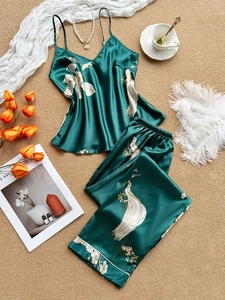 Flat lay of emerald green satin pajama set with elegant floral and crane prints