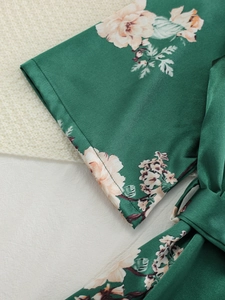 Detailed macro view of green floral satin robe featuring wide cuffs and a matching belt