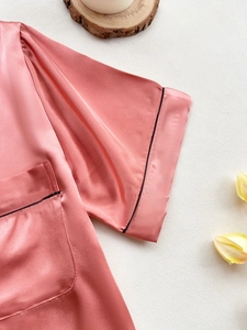 Detail view of pink satin pajama with black piping trim and elegant tulip decoration