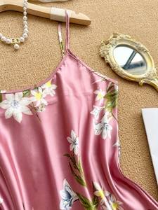 Detailed view of pink floral satin slip dress with thin straps on woven background
