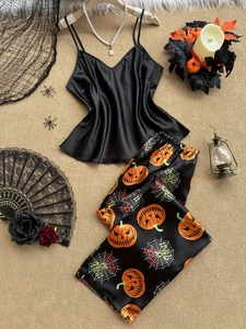 Dettaglio del pigiama di Halloween in raso con stampe di zucca e oggetti decorativi spooky