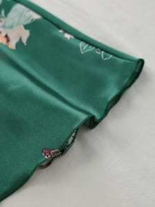 Detail of floral satin nightgown with elegant overlock stitching and silky leaf patterns