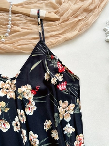 Detailansicht eines schwarzen Satin-Blumenkleides mit feinen Trägern und V-Ausschnitt