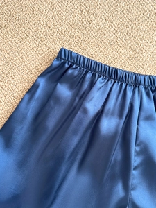 Detail of the elastic waistband on blue satin pajama shorts with smooth silk-like texture
