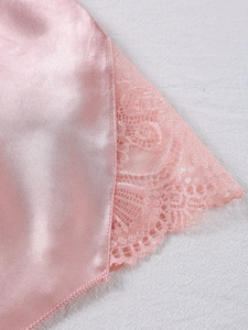 Close-up of pink satin fabric with delicate floral lace trim on women's pajama set