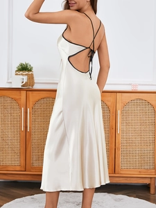 Champagne satin dress with black trim, open back and cross straps in a cozy home setting