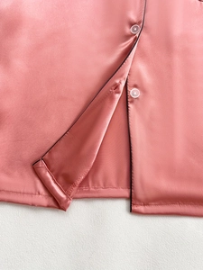 Detail of pink silk pajamas with black piping, white buttons and smooth satin texture