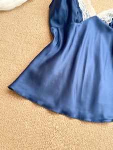 Detail of dark blue satin pajama top with delicate white floral lace trim on neckline