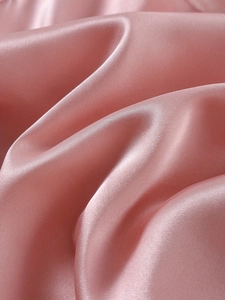 Close-up of pink satin fabric showing silky texture and smooth drape of the pajamas