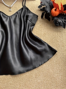 Dettaglio della canotta in raso nero con zucca di Halloween e collana di perle