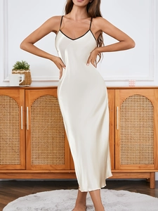 Detail of white satin slip dress with black contrast trim and luxurious glossy texture