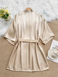 Flat lay of champagne silk satin robe with matching tie belt on luxury decor background