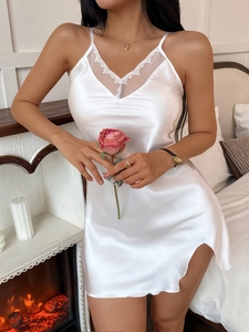 Close-up of elegant white satin nightdress with delicate lace trim and side slit detail
