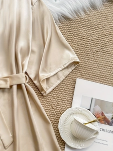 Detail of champagne gold satin robe with elegant tie belt and metallic buckle hardware