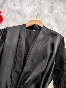 Dettaglio della vestaglia in raso nero con maniche in pizzo e scollatura a V elegante