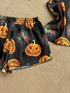 Detail of Halloween satin sleepwear featuring pumpkin and spider web prints on black fabric