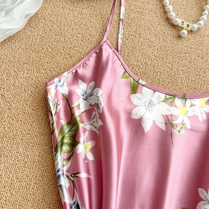 Pink satin floral sleep dress with delicate straps on a textured woven background