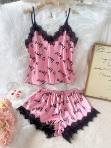 Détail d'un pyjama en soie rose avec imprimé love et bordure en dentelle noire délicate