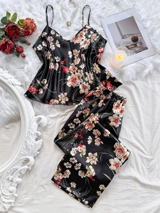 Set pigiama in raso nero a fiori con canotta e pantaloni su sfondo di finta pelliccia bianca