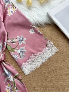 Détail de la manche d'un peignoir en satin rose fleuri avec bordure en dentelle blanche