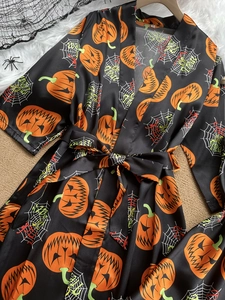 Detail of silk-like Halloween robe showing vivid pumpkin prints and Happy Halloween text