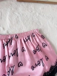 Vue détaillée du short en satin rose avec bordure en dentelle noire et motifs