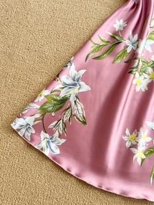 Close-up of pink satin nightdress with white lily floral print and smooth silky texture