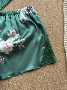 Dettaglio degli shorts in raso verde scuro con fiori, pizzo e vita elasticizzata