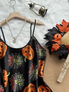 Detail of Halloween silk satin slip dress featuring pumpkin and spider web festive prints