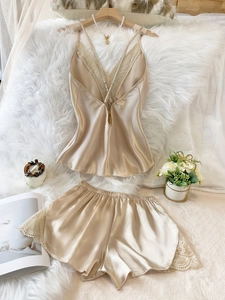 Detail von champagnerfarbenem Satin-Pyjama mit Spitze auf weißem Plüschhintergrund