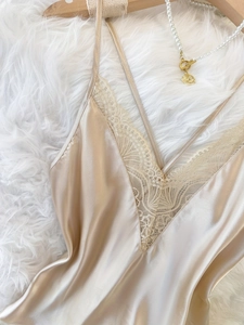 Detail von champagnerfarbenem Satin-Nachthemd mit V-Ausschnitt und Spitze auf Teppich