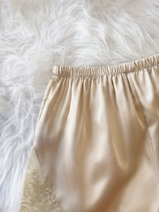 Nahaufnahme der champagnerfarbene Satin-Shorts mit Gummizug und zarter Blumen-Spitzenverzierung