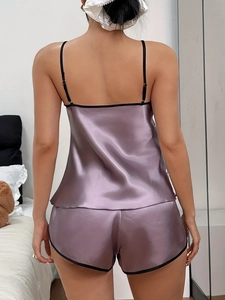 Vue arrière d'un ensemble de pyjama en satin lilas avec liseré noir dans une chambre