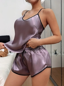 Détail d'un ensemble pyjama en satin lilas avec liseré noir et texture brillante