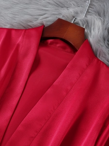 Detail of red satin robe fabric with silky texture on grey plush background